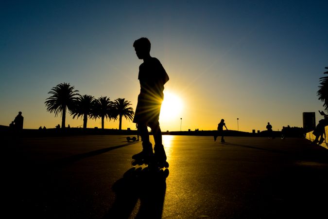 Silhouette of person rollerskating at sunset