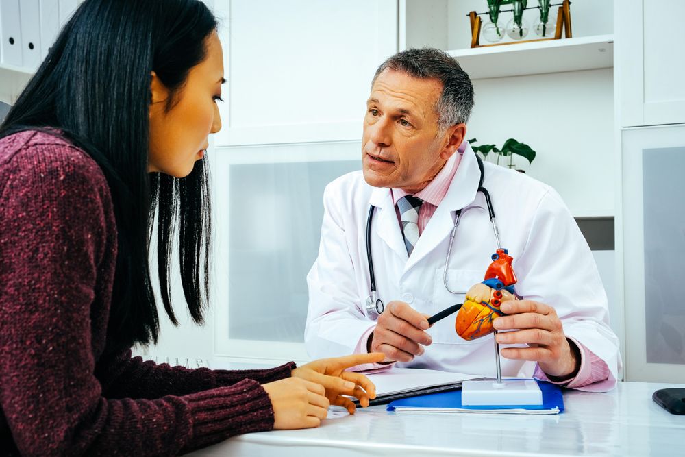 Male doctor with female patient consulting about heart structure