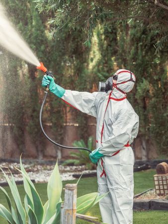 Fumigator in uniform spraying substance on garden