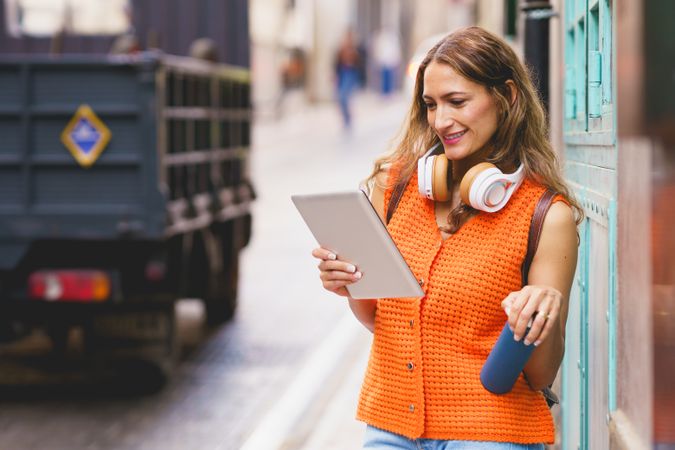 Latina woman holding reusable water bottle while using digital tablet