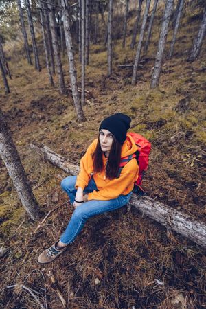 Female hiker sitting on fallen tree in autumn forest