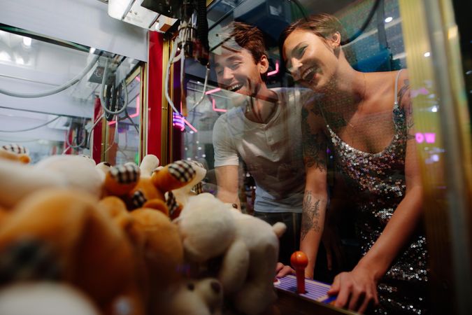 Smiling couple playing coin operated games at a gaming parlour