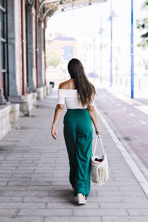 elegant confident businesswoman walking on the street carrying a purse.