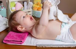 Side view of cute baby playing with towel during diaper change 41zxlb