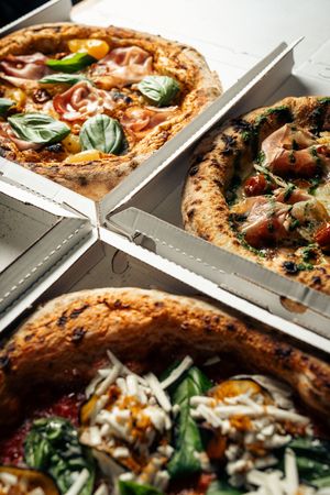 Authentic gourmet pizza with basil and toppings in takeout boxes