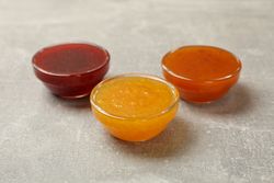 Bowls with jam on gray background, close up