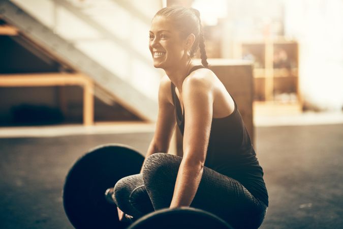 Woman smiling with barbell on floor