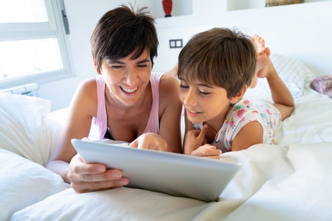 Woman laughing at something on tablet with her daughter