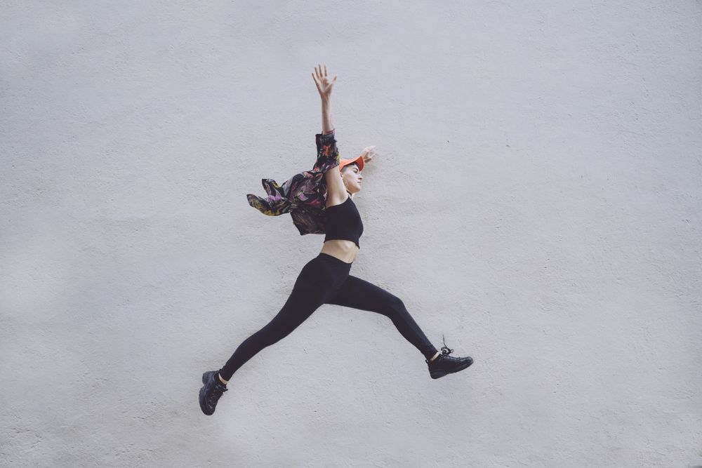 Woman jumping high along wall
