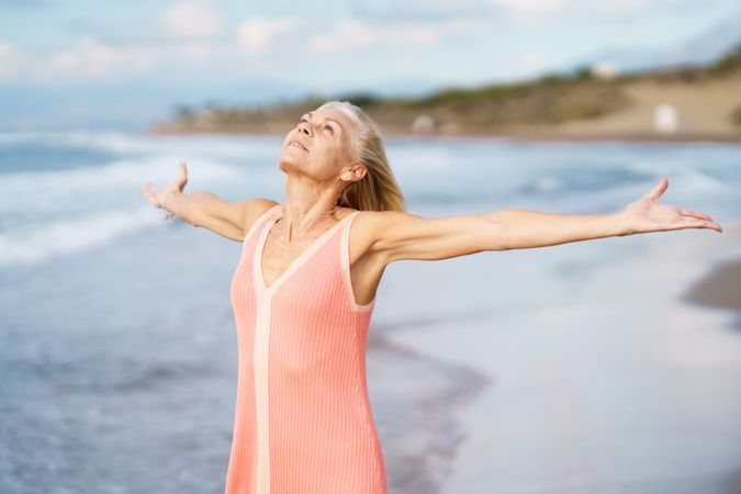 Content woman standing on the coast with her arms outstretched