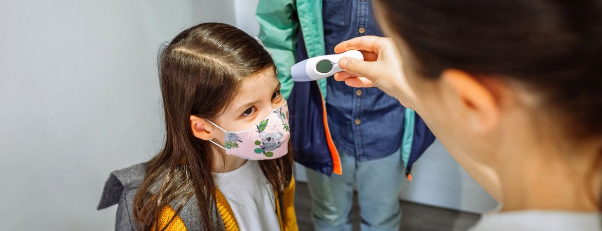 Mother checking her daughter's temperature before going to school