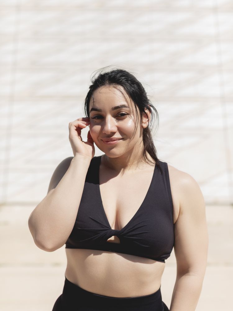 Natural portrait of a young woman with straight dark hair, happy, looking at the camera, after a sports and exercise session outdoors