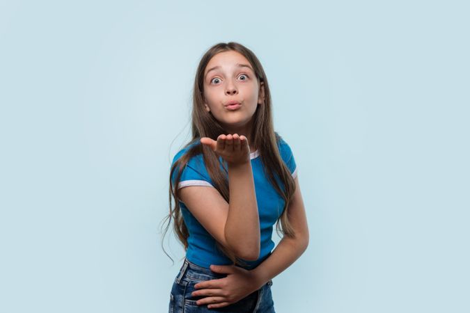 Girl in blue shirt blows a kiss towards the camera