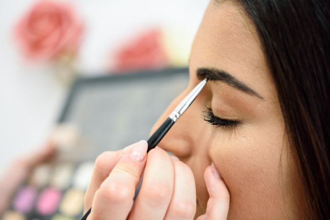 Person putting make-up on woman's eyebrow