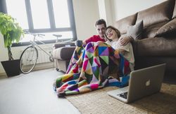 Couple wrapped in plaid watching laptop