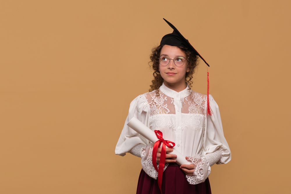 Young graduate in cap and gown holding diploma scroll