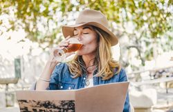 Woman sitting outside cafe drinking beer