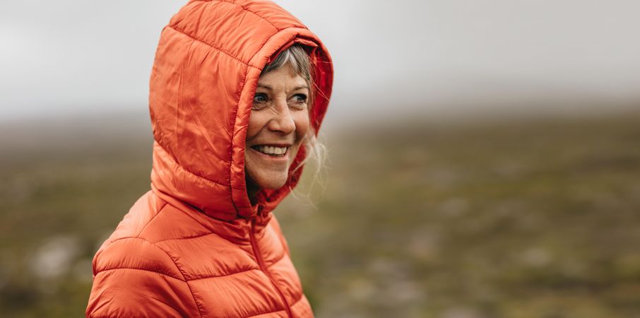 Smiling woman in a warm hooded jacket standing outdoors