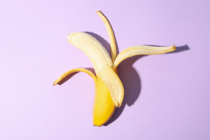 Opened banana on violet background. Fresh fruit