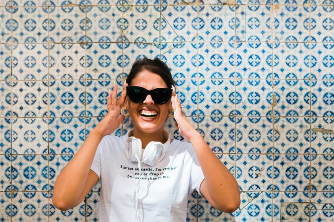 Cheerful casual woman in sunglasses standing on city street