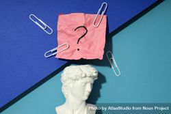 Marble bust of David with crumpled pink post it note with question mark and paper clips, closeup 0LGVgb