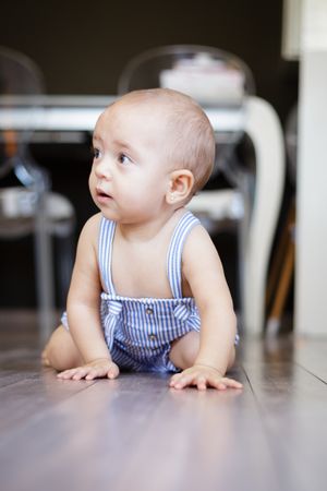 Happy baby sitting on floor in kitchen