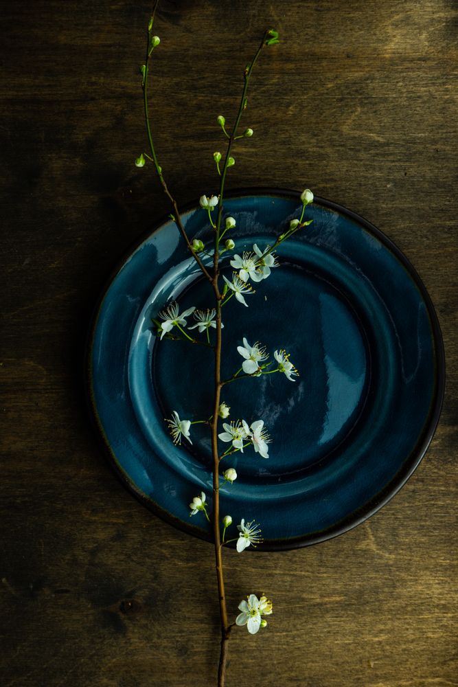 Top view of spring table setting with blooming tree branch on blue plate