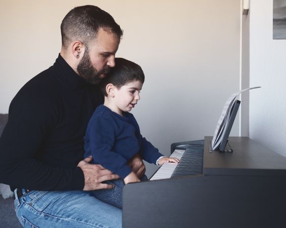 Father teaching son to play piano