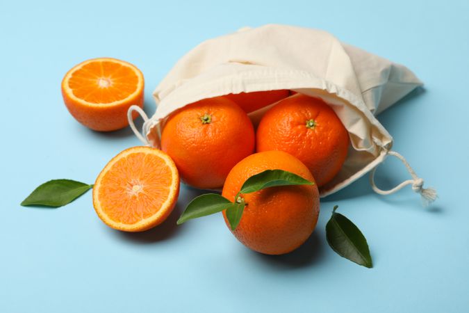 Cotton bag with ripe mandarins on blue background