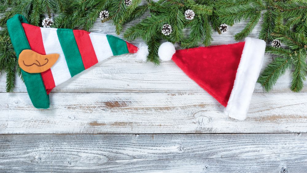 Christmas fir branches along with traditional hat decorations on rustic wooden background