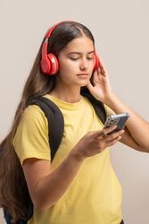 Young student listening to music on headphones while using her smartphone.