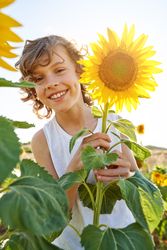 Happy child with blooming sunflower on meadow
