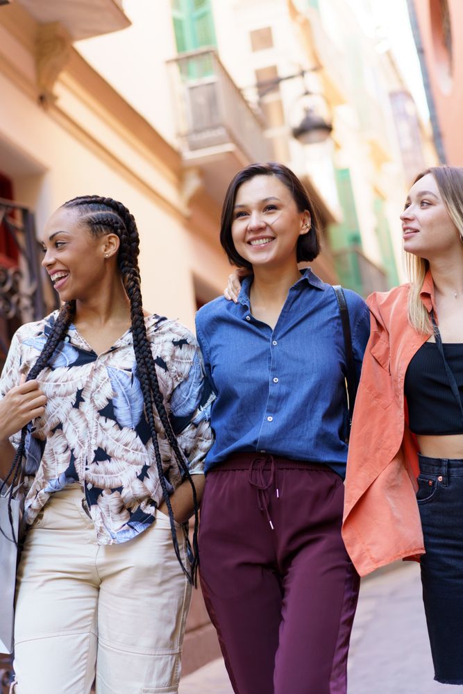 Three happy women enjoying their walk through street, vertical