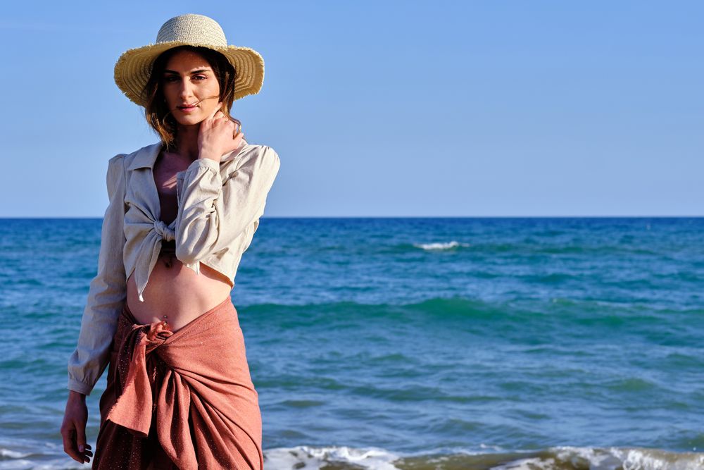 A fashion model with a hat at the beach before sunset