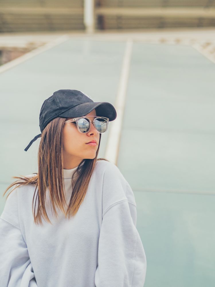 Young woman with glasses standing against wall