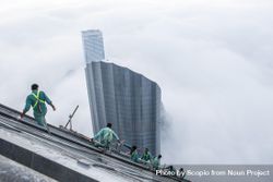 Top view of workers attached to a skyscraper under construction above the clouds in in Dubai, UAE 5pyMv4