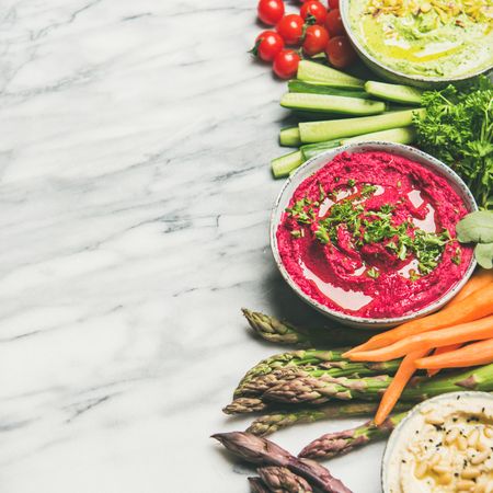 Fresh colorful vegetables and dips with hummus, avocados, asparagus, square crop with copy space