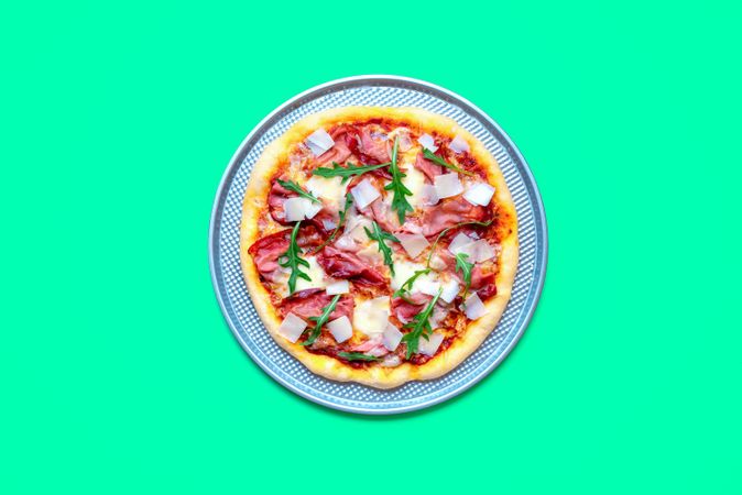 Homemade prosciutto pizza minimalist on a green table