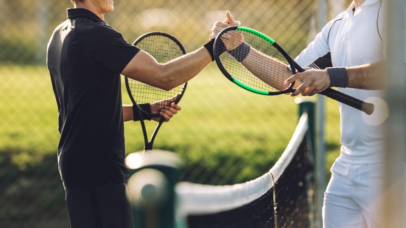 Two young man shaking hands after playing tennis