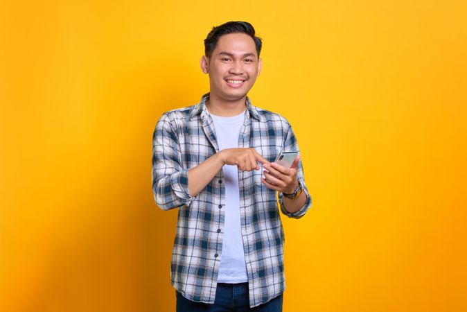 Smiling Asian male looking up from his phone