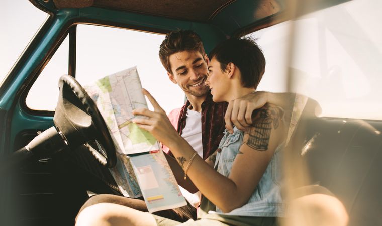 Happy couple picking out road trip destination with paper map