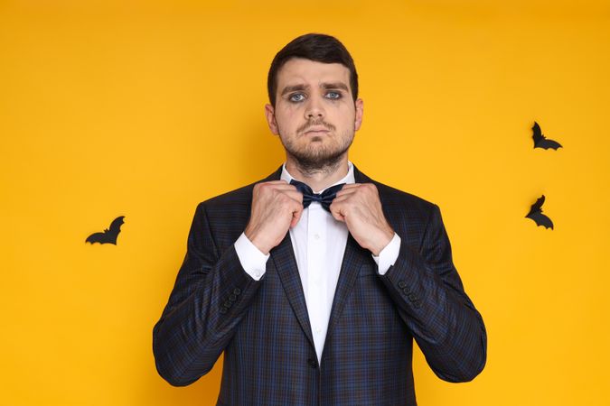 A man in a business suit with zombie makeup on a yellow background