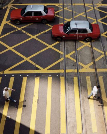 Top view of two cars on the road while people walking on pedestrian lane