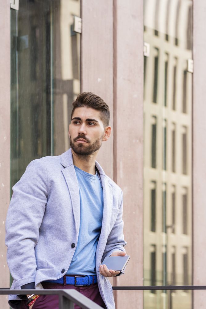Man holding his mobile phone standing outside building, vertical