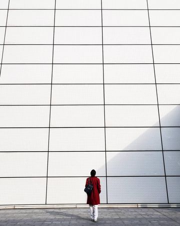Back view of person in red coat standing against light checkered wall