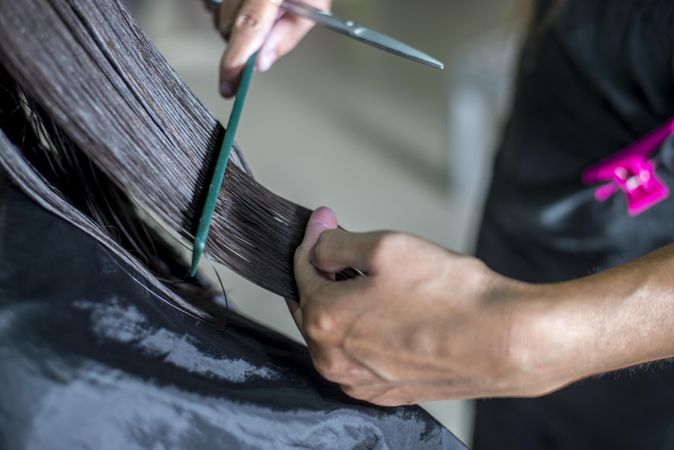 Brunette with newly washed hair being cut in salon