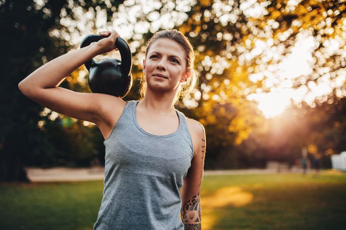 Portrait of fit young woman with kettlebell weights in the park