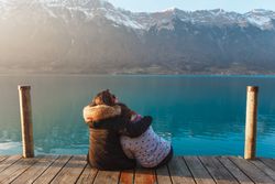 Embracing women on pier in mountains