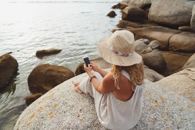 Contemporary woman with phone chilling on seashore