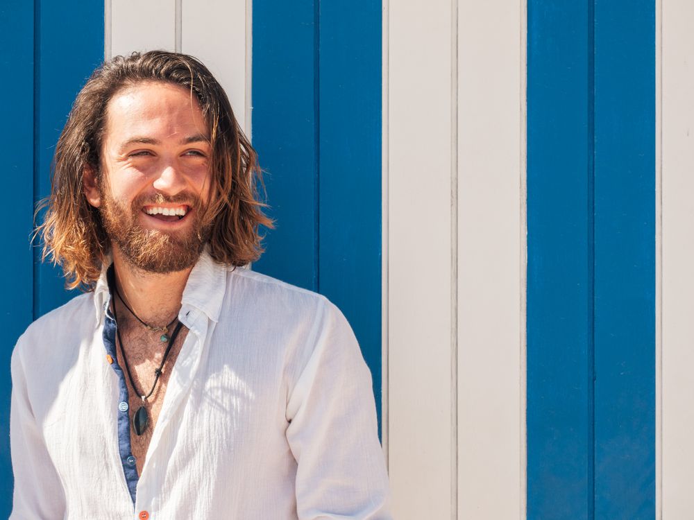 Cheerful guy standing near striped wall